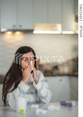 Woman blowing nose into tissue feeling unwell and sick Woman blowing nose into tissue feeling unwell and sick 138432961
