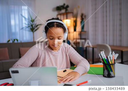 Young girl learning drawing online with wireless headphones Young girl learning drawing online with wireless headphones 138433489