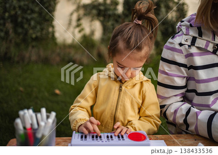 Young girl playing toy piano outdoors learning music Young girl playing toy piano outdoors learning music 138433536