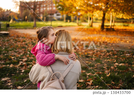 Daughter sharing secret with mother in autumn park Daughter sharing secret with mother in autumn park 138433700