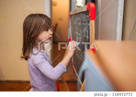 Young girl drawing on small blackboard with chalk Young girl drawing on small blackboard with chalk 138433772