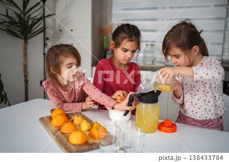 Girls making fresh orange juice in kitchen at home Girls making fresh orange juice in kitchen at home 138433784