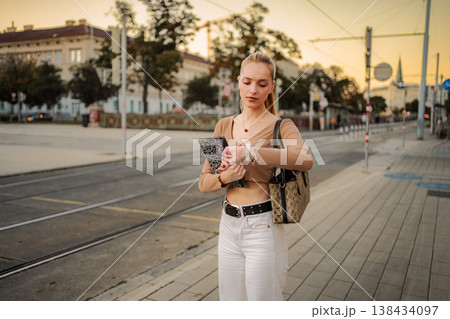 Young woman checking smartwatch on Vienna city street at sunset Young woman checking smartwatch on Vienna city street at sunset 138434097