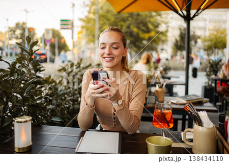 Smiling woman using smartphone at outdoor cafe in Vienna 138434110