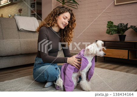 Woman drying white dog with purple towel after bath 138434164