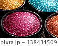 Close-up of vibrant glitter eyeshadow palettes in gold, pink, teal, and bronze shades 138434509