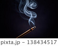 Close-up of incense stick burning and releasing smoke against a dark background 138434517