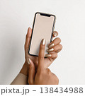 Woman Hand With Matte Gold Nails Using Smartphone and Tapping Screen Close Up 138434988