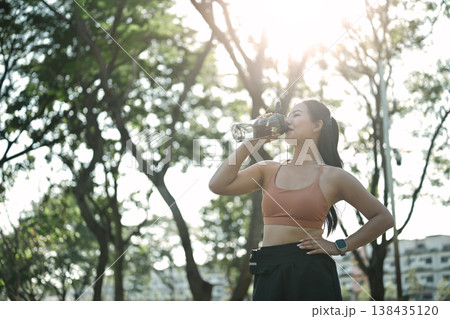 Fit female athlete with a water bottle and taking a break after exercise Fit female athlete with a water bottle and taking a break after exercise 138435120