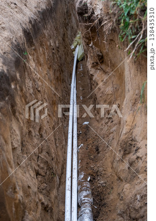 Insulated water pipe in earth trench, underground installing, utility line, site groundwork, plumbing protection, channel excavation, dirt covering, repair. Insulated water pipe in earth trench, underground installing, utility line, site groundwork, plumbing protection, channel excavation, dirt covering, repair. 138435310