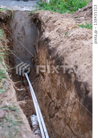 Trench for laying insulated supply pipes, plumbing line installation, groundwork, protection against frost, maintenance, construction earthworks, repair job. Trench for laying insulated supply pipes, plumbing line installation, groundwork, protection against frost, maintenance, construction earthworks, repair job. 138435313