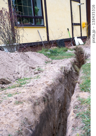 Narrow trench excavation for insulated pipe, utility line laying, groundwork site, channel insulation, water supply, protection, construction, installation work. Narrow trench excavation for insulated pipe, utility line laying, groundwork site, channel insulation, water supply, protection, construction, installation work. 138435316