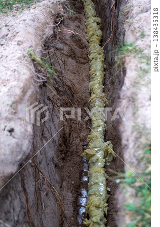 Insulated water pipeline in ground, plumbing protection, trenchwork installation, covered utility tube, groundwork, residential, repair, site, channel excavation. Insulated water pipeline in ground, plumbing protection, trenchwork installation, covered utility tube, groundwork, residential, repair, site, channel excavation. 138435318