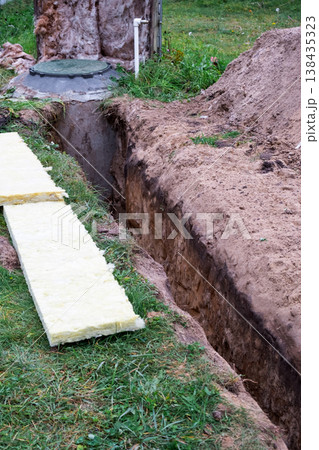 Prepared trench for laying insulation, water pipe protection, groundwork, thermal cover, utility supply, residential plumbing, installation, outdoor construction, repair. Prepared trench for laying insulation, water pipe protection, groundwork, thermal cover, utility supply, residential plumbing, installation, outdoor construction, repair. 138435323