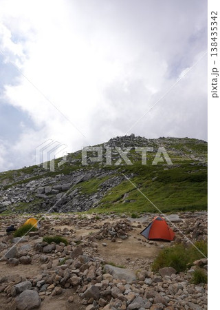 山頂でテントを張って宿泊する登山家 山頂でテントを張って宿泊する登山家 138435342
