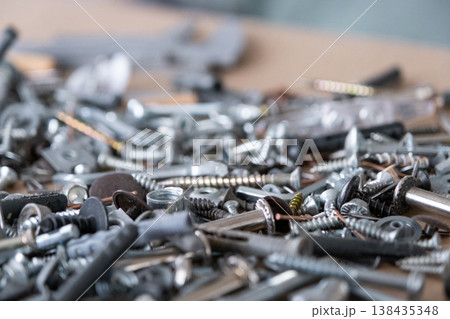 Pile of metal fasteners: bolts, nuts, screws, washers and nails, essential for repair, assembly, construction, and production works in workshops. Pile of metal fasteners: bolts, nuts, screws, washers and nails, essential for repair, assembly, construction, and production works in workshops. 138435348