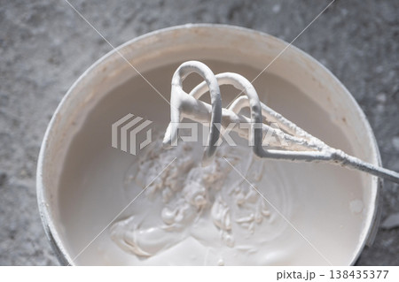 Mixing plaster and putty with a drill mixer, construction preparation, building renovation, even consistency for wall finishing and repair work. Mixing plaster and putty with a drill mixer, construction preparation, building renovation, even consistency for wall finishing and repair work. 138435377