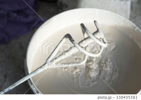 Container with putty compound and mixer blade, solution mixing for plastering, home repair, renovation tasks, equipment for wall surface prepping. Container with putty compound and mixer blade, solution mixing for plastering, home repair, renovation tasks, equipment for wall surface prepping. 138435381