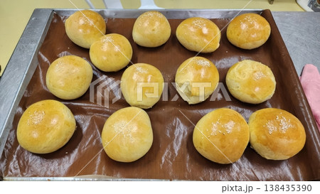 Freshly Baked Golden Brown Bread Rolls with Sesame Seeds on a Baking Tray 138435390