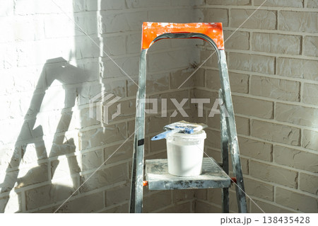 Painting process in progress, stepladder and paint tools, renovation of inner walls, interior finish, home decor and wall protection. Painting process in progress, stepladder and paint tools, renovation of inner walls, interior finish, home decor and wall protection. 138435428