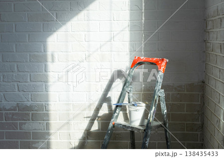 Room painting and decorating, stepladder with paint bucket, surface prep for wall finishing, interior remodeling, professional upgrade. 138435433