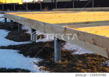 View of screw pile foundation, timber platform and base beams, frame house construction phase, groundwork site, preparation, mounting substructure, support setup. View of screw pile foundation, timber platform and base beams, frame house construction phase, groundwork site, preparation, mounting substructure, support setup. 138435466