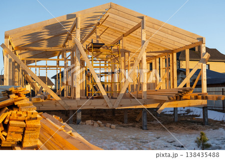 Frame house assembling, wooden skeleton, beams, posts in place, bracing elements, foundation support, modern carpentry, site construction progress, installation. Frame house assembling, wooden skeleton, beams, posts in place, bracing elements, foundation support, modern carpentry, site construction progress, installation. 138435488