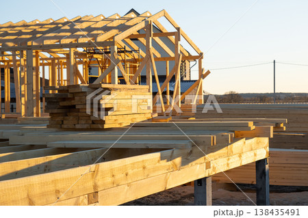 Timber beams on foundation, wood frame structure, skeleton mounting, assembly stage of construction, bracing, carpentry, modern building, exterior site, workplace. Timber beams on foundation, wood frame structure, skeleton mounting, assembly stage of construction, bracing, carpentry, modern building, exterior site, workplace. 138435491
