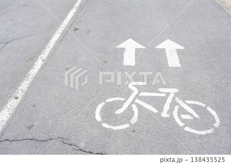 Bicycle path sign and arrows painted on city road, safe route for cyclists, urban road marking, following traffic rules. Bicycle path sign and arrows painted on city road, safe route for cyclists, urban road marking, following traffic rules. 138435525