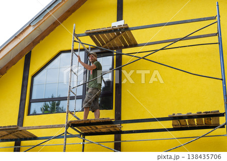 Scaffolded wall painting, finishing paint over plaster, exterior color renovation, timber board decoration for half-timber motif, surface completion, modern look. Scaffolded wall painting, finishing paint over plaster, exterior color renovation, timber board decoration for half-timber motif, surface completion, modern look. 138435706
