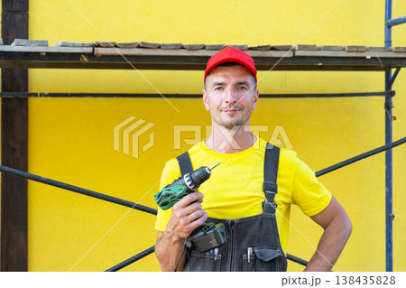 Construction worker with electric drill, home building site, DIY renovations, private client, handy tool set, home service visit, carpentry and repairs. Construction worker with electric drill, home building site, DIY renovations, private client, handy tool set, home service visit, carpentry and repairs. 138435828
