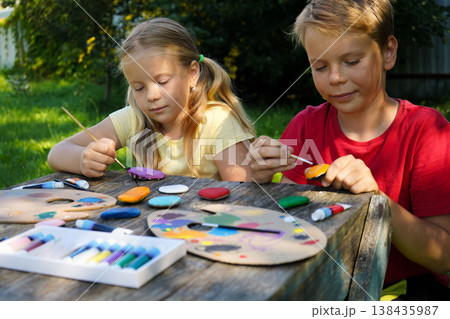 Artistic kids transform ordinary stones into playful art, creating one-of-a-kind handmade gifts to cherish. Artistic kids transform ordinary stones into playful art, creating one-of-a-kind handmade gifts to cherish. 138435987