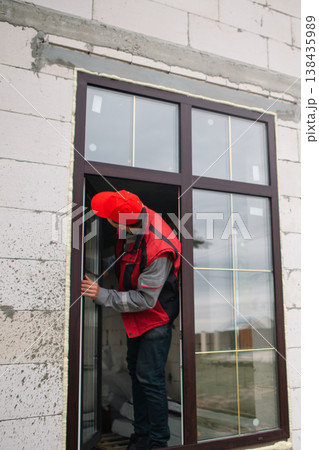 Technician adjusts plastic window in brick wall, installation process, regulating new PVC window, precision work, modern house fitting and home improvement. Technician adjusts plastic window in brick wall, installation process, regulating new PVC window, precision work, modern house fitting and home improvement. 138435989
