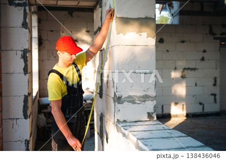 Worker measures window height and wall for installation, interior remodeling, marking partition for fitting windows and doors, room improvement and repair. 138436046