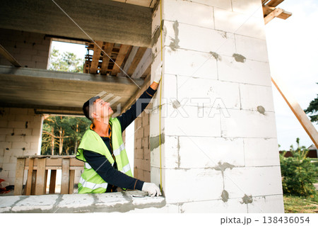 Construction worker monitors build quality, inspects masonry, verifies fit, alignment, and finishing, teamwork action, site control, safety adherence, project task. Construction worker monitors build quality, inspects masonry, verifies fit, alignment, and finishing, teamwork action, site control, safety adherence, project task. 138436054