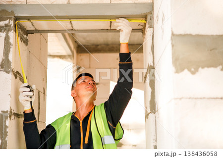 Builder positions ceiling segment, prepares for installation, teamwork coordination, technical assistance, interior finish, repair, structural progress, site check. Builder positions ceiling segment, prepares for installation, teamwork coordination, technical assistance, interior finish, repair, structural progress, site check. 138436058