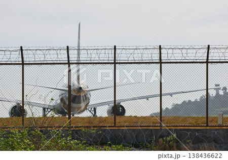 A huge passenger plane pulls onto the runway of Thailand airport, a view through the fence A huge passenger plane pulls onto the runway of Thailand airport, a view through the fence 138436622