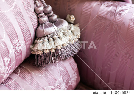 Soft pink tassel tieback draped over cushions Soft pink tassel tieback draped over cushions 138436825