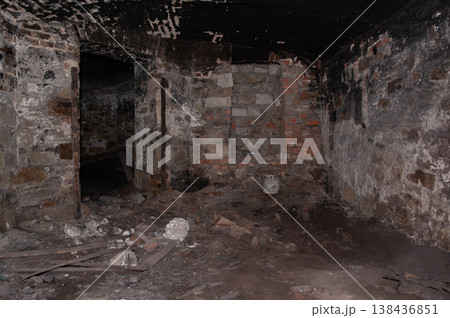Abandoned Stone Basement Interior With Charred Brick Walls And Debris Scattered On Floor In Dark Atmospheric Setting Showing Decay And Ruin 138436851