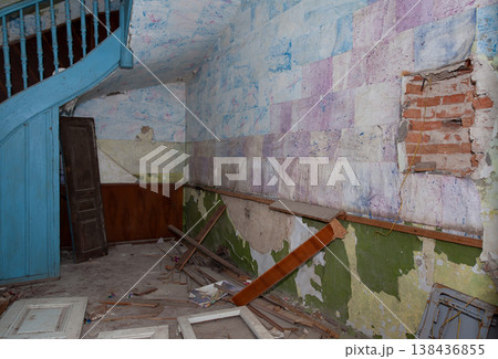 Abandoned Victorian Interior Showing Peeling Paint Layers Over Brick Walls With Blue Staircase And Scattered Debris In Dilapidated State 138436855