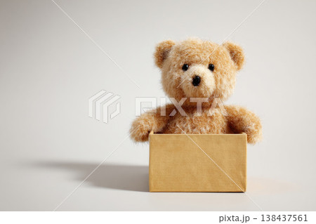 Teddy bear in a cardboard box on a light background. Space for text. Teddy bear in a cardboard box on a light background. Space for text. 138437561