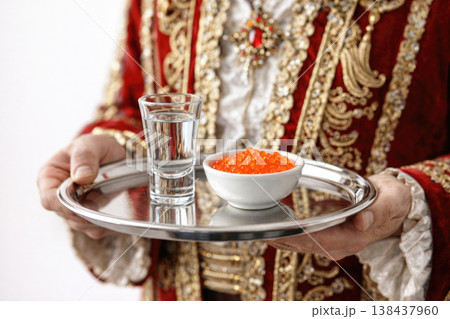 A man in a red suit holds a tray with caviar and a glass. A man in a red suit holds a tray with caviar and a glass. 138437960