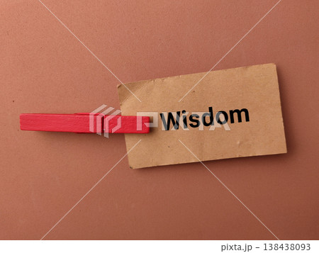 high-angle conceptual shot on a warm brown background featuring a small piece of brown kraft paper with the word Wisdom. high-angle conceptual shot on a warm brown background featuring a small piece of brown kraft paper with the word Wisdom. 138438093
