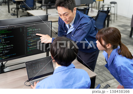 ベテラン技術者が若手と画面を共有しながらプログラム修正を行う現場 ベテラン技術者が若手と画面を共有しながらプログラム修正を行う現場 138438166