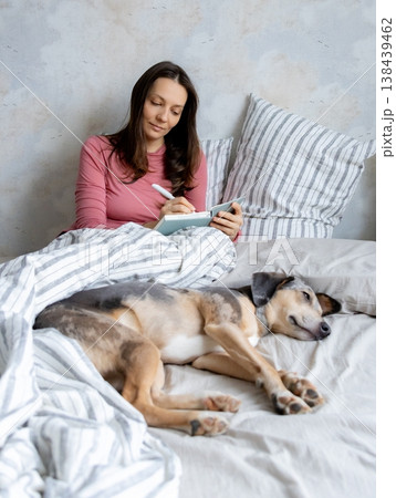 woman in bed writes in personal diary, writes down emotions, writes down wish list. mental health. 138439462