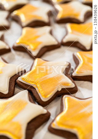 A collection of gingerbread star cookies decorated with royal icing and painted with vibrant gold luster dust, beautifully arranged for a festive look. A collection of gingerbread star cookies decorated with royal icing and painted with vibrant gold luster dust, beautifully arranged for a festive look. 138439626