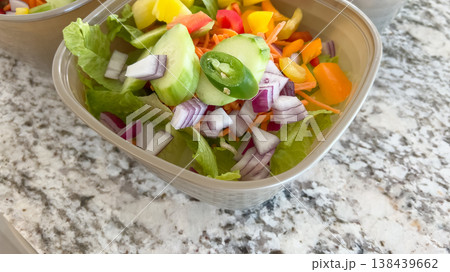 A close-up image of a fresh chopped salad in a container featuring a jalapeno slice on top with red onion, bell peppers, and shredded carrots. A close-up image of a fresh chopped salad in a container featuring a jalapeno slice on top with red onion, bell peppers, and shredded carrots. 138439662