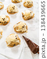 Overhead view of iced cookies arranged on parchment paper with a piping bag nearby. The bright background and soft lighting create a clean cookie decorating layout. 138439665