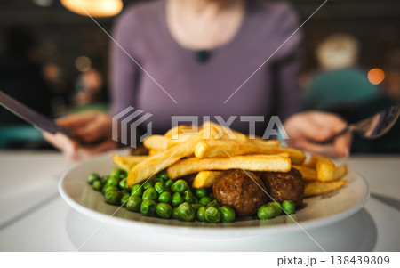Girl Eating French Fries With Vegetables And Grilled Meatballs In A Cafe Girl Eating French Fries With Vegetables And Grilled Meatballs In A Cafe 138439809