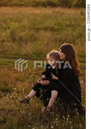 Gentle Mother Guides Young Girl Through Blooming Wildflowers In Bright Meadow Setting 138440269